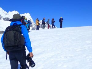 People in Antarctica on snowy landscape with mountains in background.